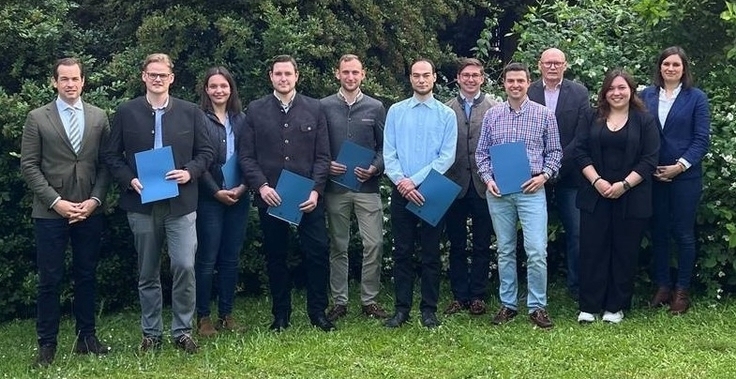 Gruppenfoto: sieben neuen Forstreferendarinnen und Forstreferendare des Prüfungsjahrgangs 2026 auf dem Rasen des ML-Gartens. Sie halten Urkunden in der Hand