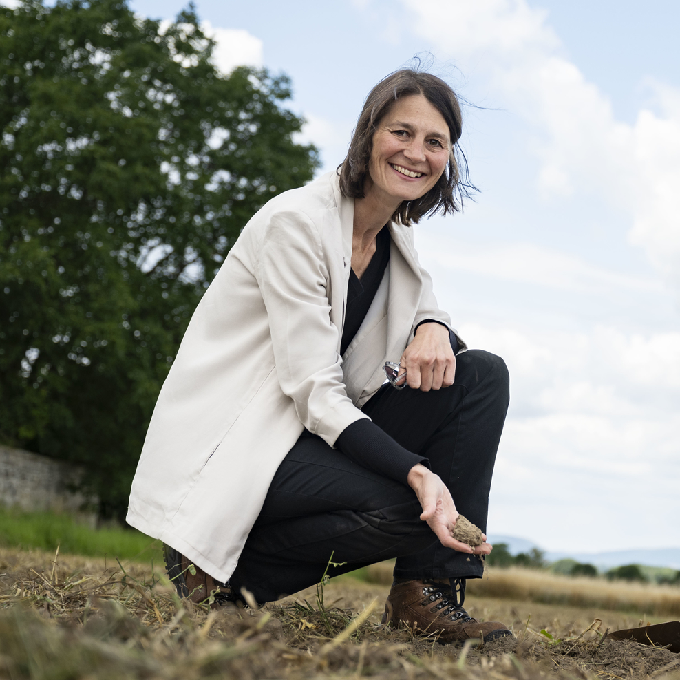 Ministerin Miriam Staudte und Landwirt Jan Wittenberg hocken auf einem Acker.