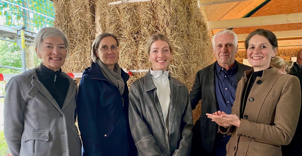 Ministerin Staudte mit den Verantwortlichen vor einem überdimensionalen Strohballen