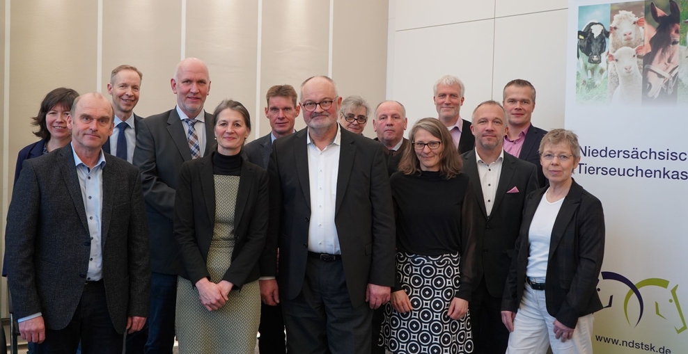 Gruppenbild von Landwirtschaftsministerin Miriam Staudte und dem Verwaltungsrat der Tierseuchenkasse und ihrem Vorsitz Georg Meiners im Sitzungssaal des Landwirtschaftsministeriums vor einem Banner der Tierseuchenkasse